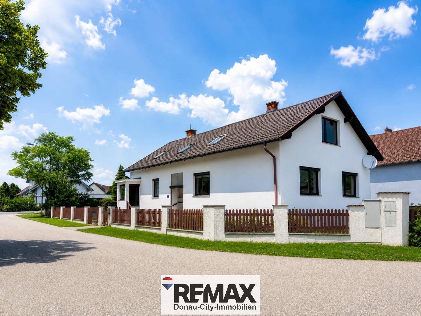 Ansicht des Hauses von der Straße mit gepflegtem Grundstück und traditionellem Zaun.