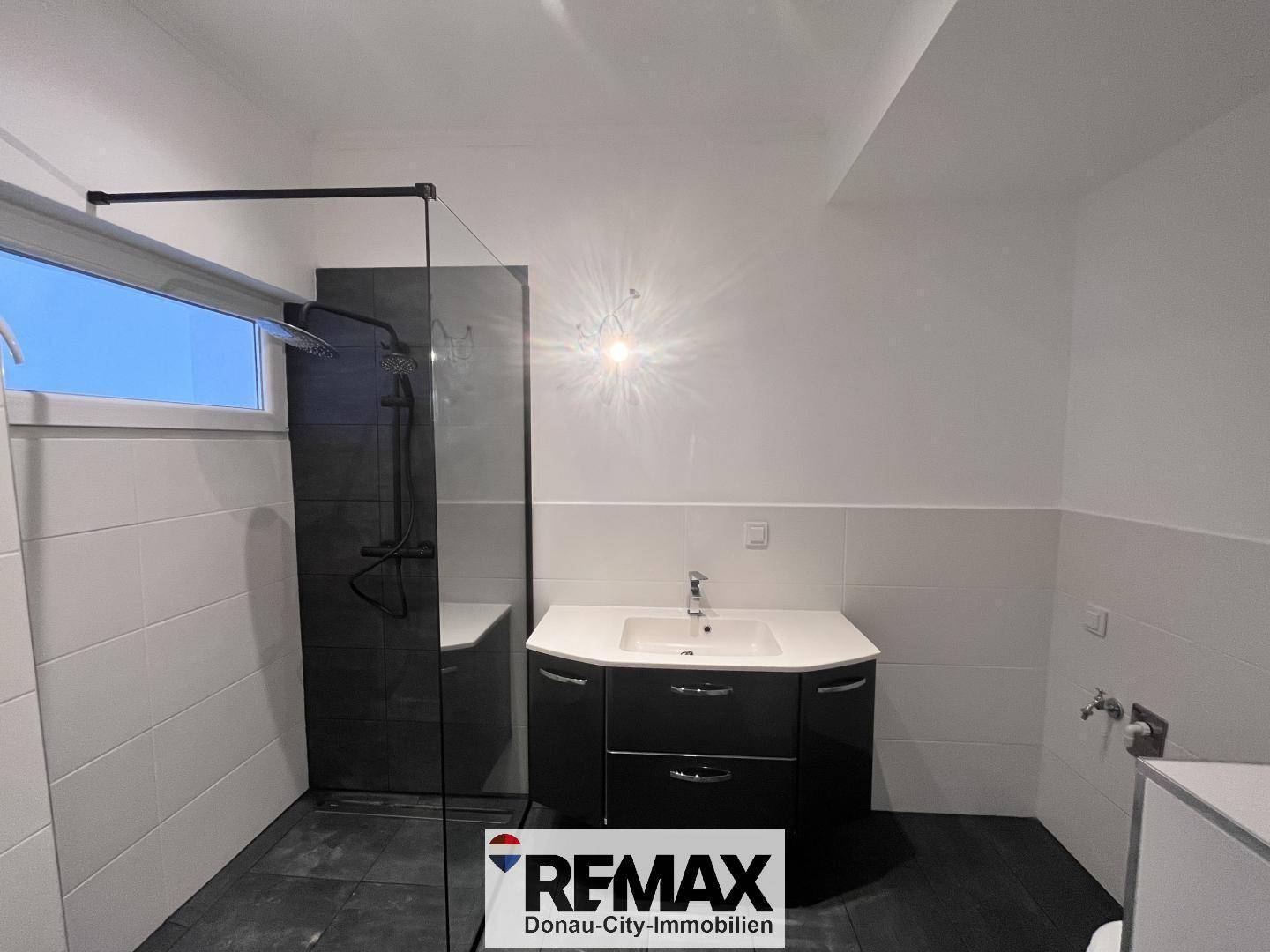 Helles Badezimmer mit begehbarer Dusche, modernem Waschtisch und weißen Wandfliesen.