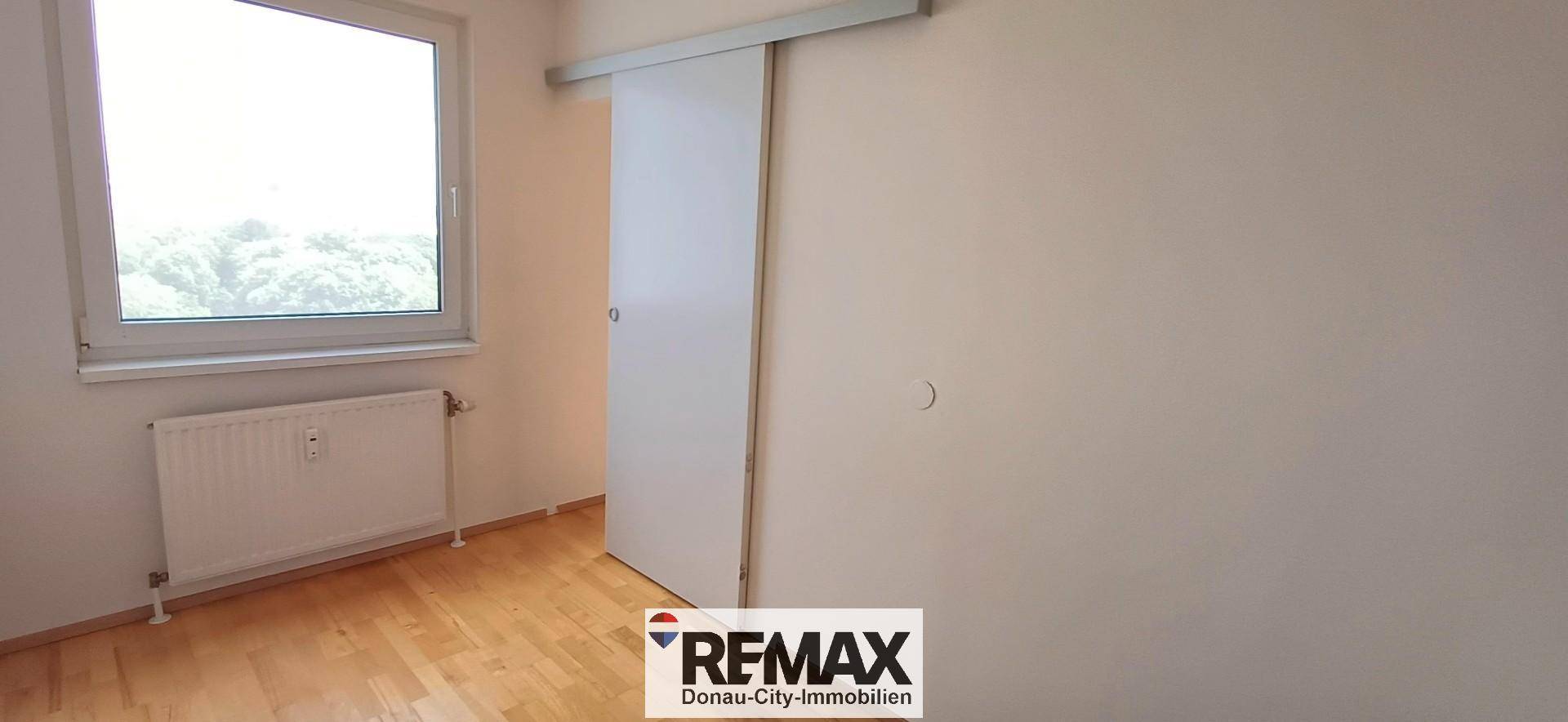 Helles Zimmer mit Holzboden, Fenster und praktischer Schiebetür, vielseitig nutzbar.
