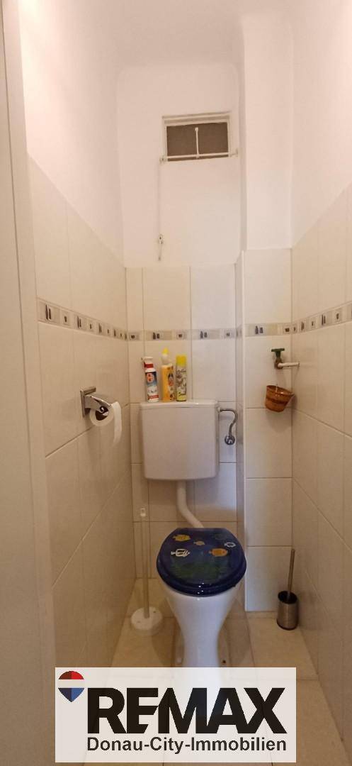 Separates WC mit Toilette und einem kleinen Fenster zur Belüftung, funktional und hell gestaltet.