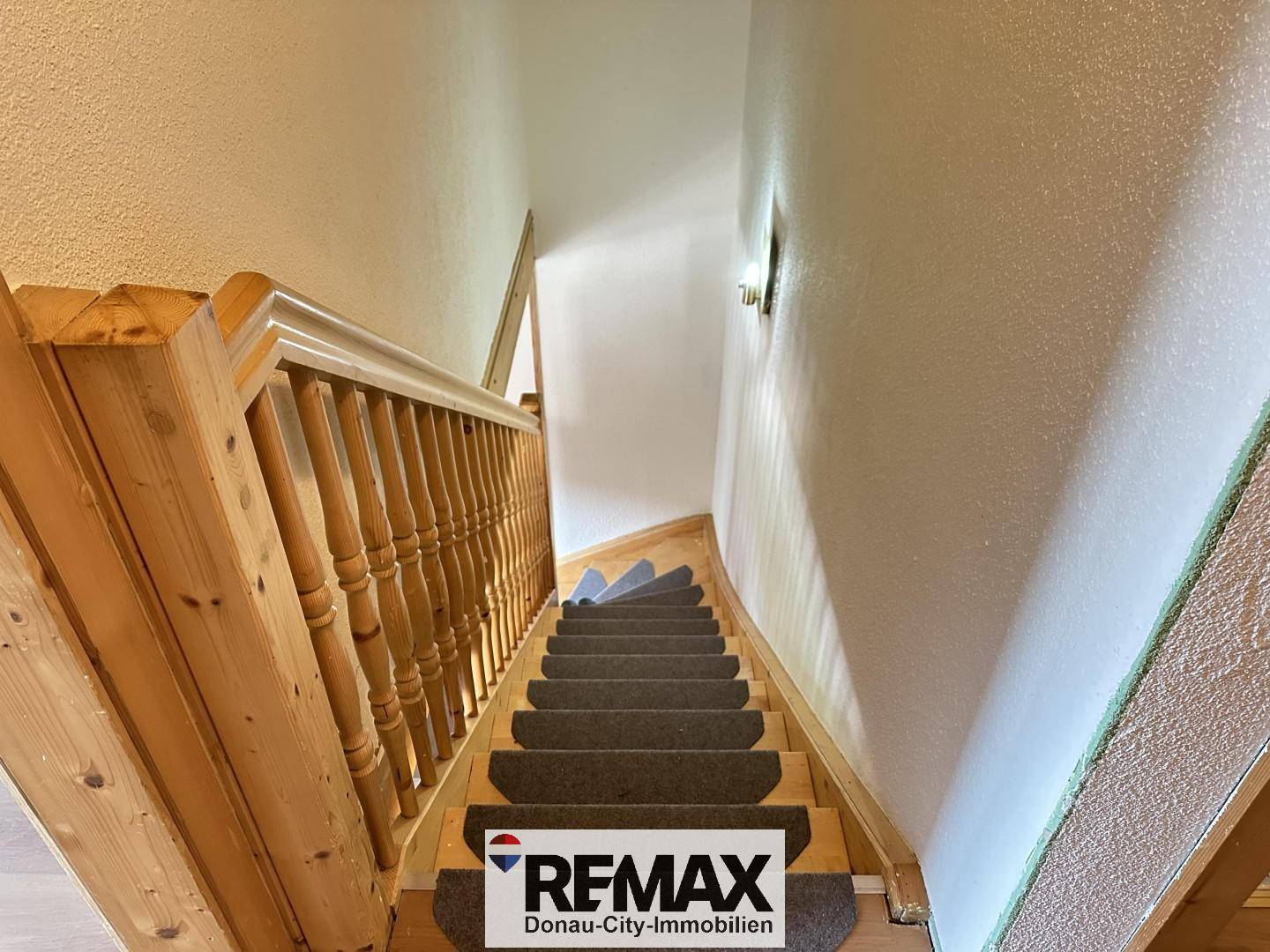 Holztreppe mit Teppichläufern führt in die oberen Etagen des Hauses.