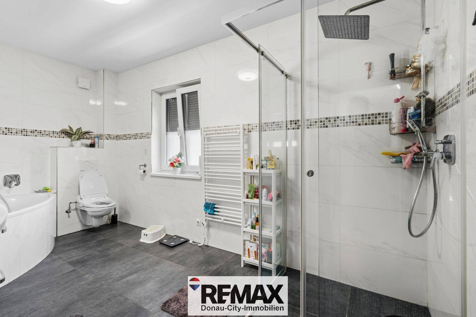 Helles Badezimmer mit großer Dusche, Badewanne und beheiztem Handtuchhalter.