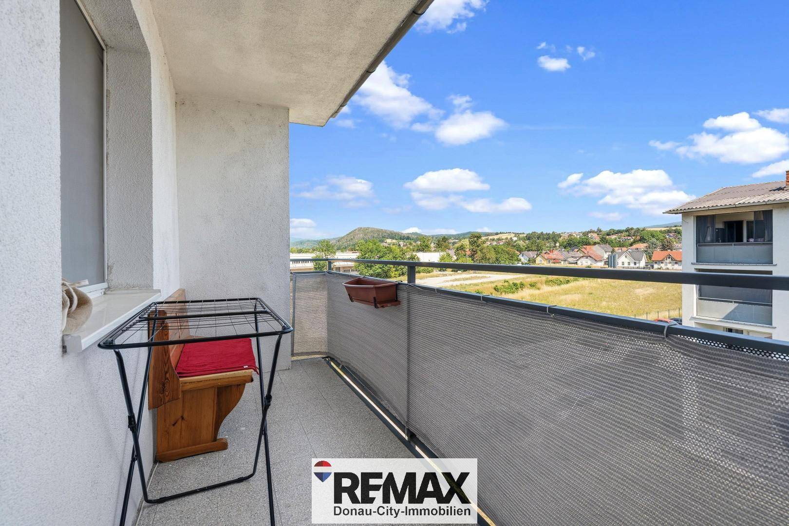 Balkon mit schöner Aussicht auf die grüne Umgebung und die Berge im Hintergrund.