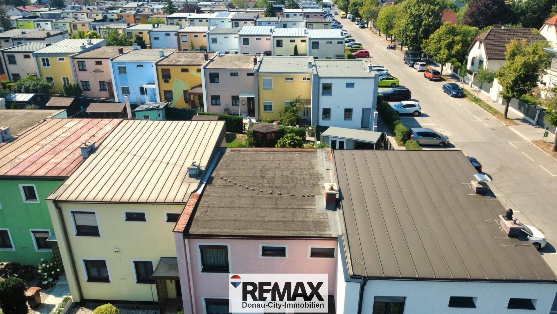 Luftaufnahme der Wohnsiedlung mit Reihenhäusern und einer Straße, die die Umgebung zeigt.