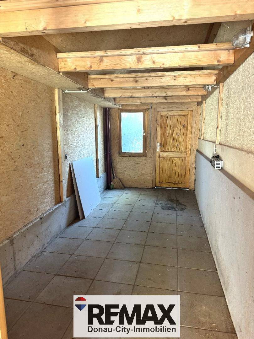 Einfacher Abstellraum oder Schuppen mit Fliesenboden und unverkleideten Holzwänden.