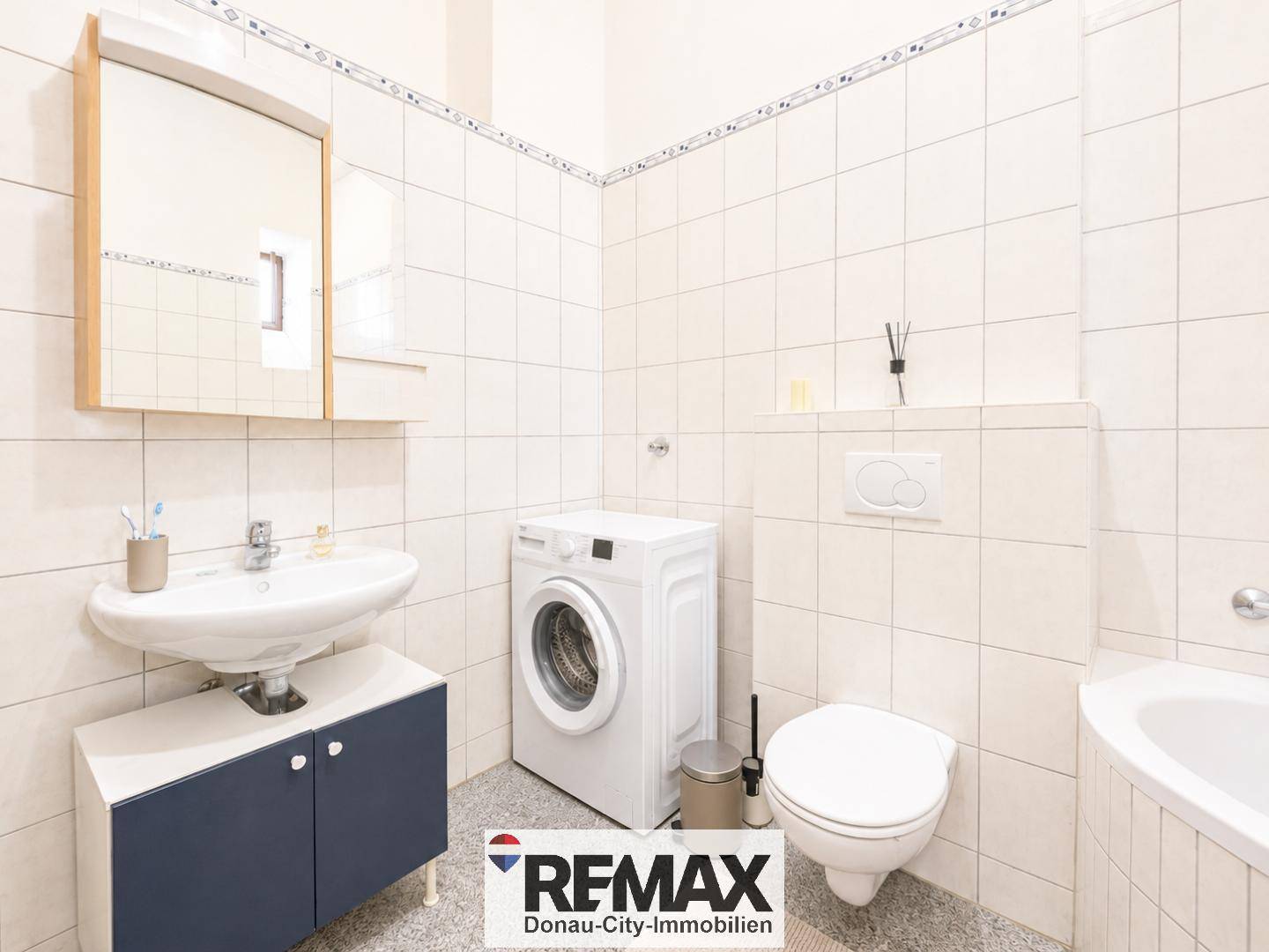 Helles Badezimmer mit Waschbecken, Spiegelschrank, Toilette und Waschmaschine.