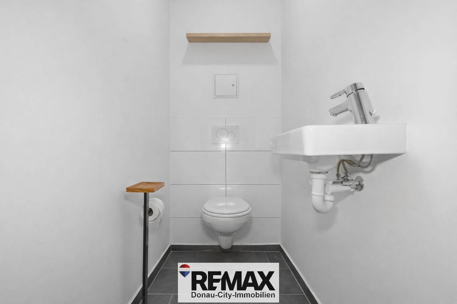 Separates Gäste-WC mit Wand-WC und kleinem Waschbecken.