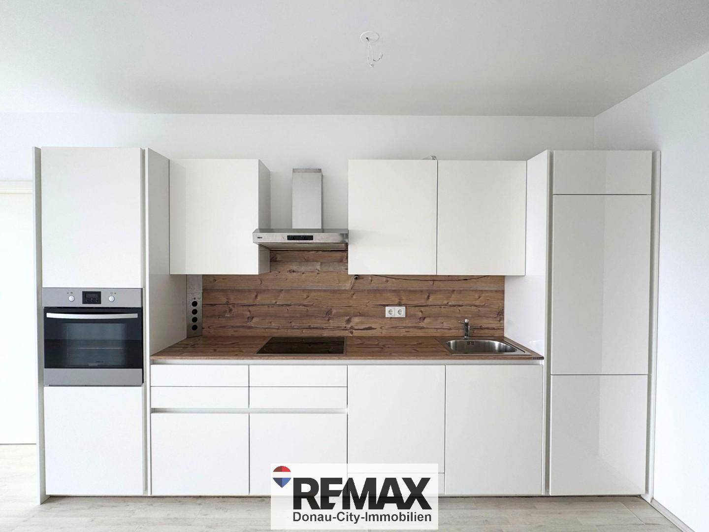 Moderne Einbauküche mit weißen Fronten, Holzdekor und integrierten Elektrogeräten.