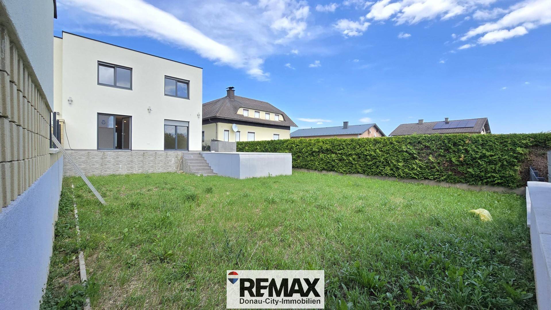 Rückansicht des Hauses mit großem, unmöbliertem Garten und viel Grünfläche.