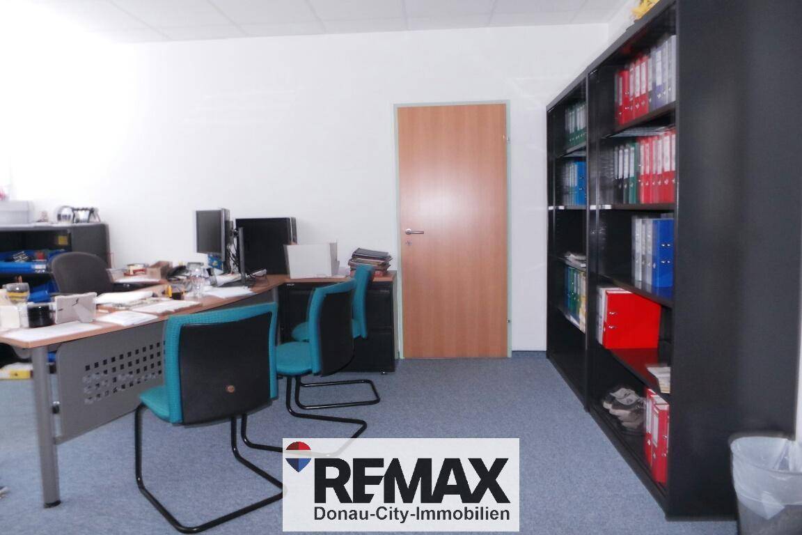 Ein funktionales Büro mit Schreibtischen, Bürostühlen und einem großen Bücherregal.