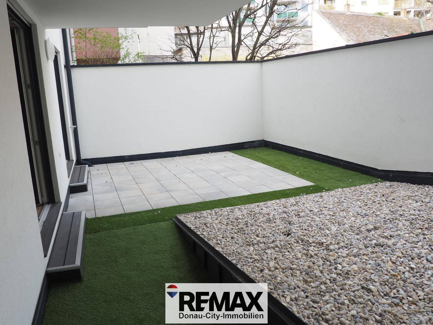 Umschlossene Terrasse mit gepflastertem Bereich, Kunstrasen und Kies, ideal zum Entspannen.