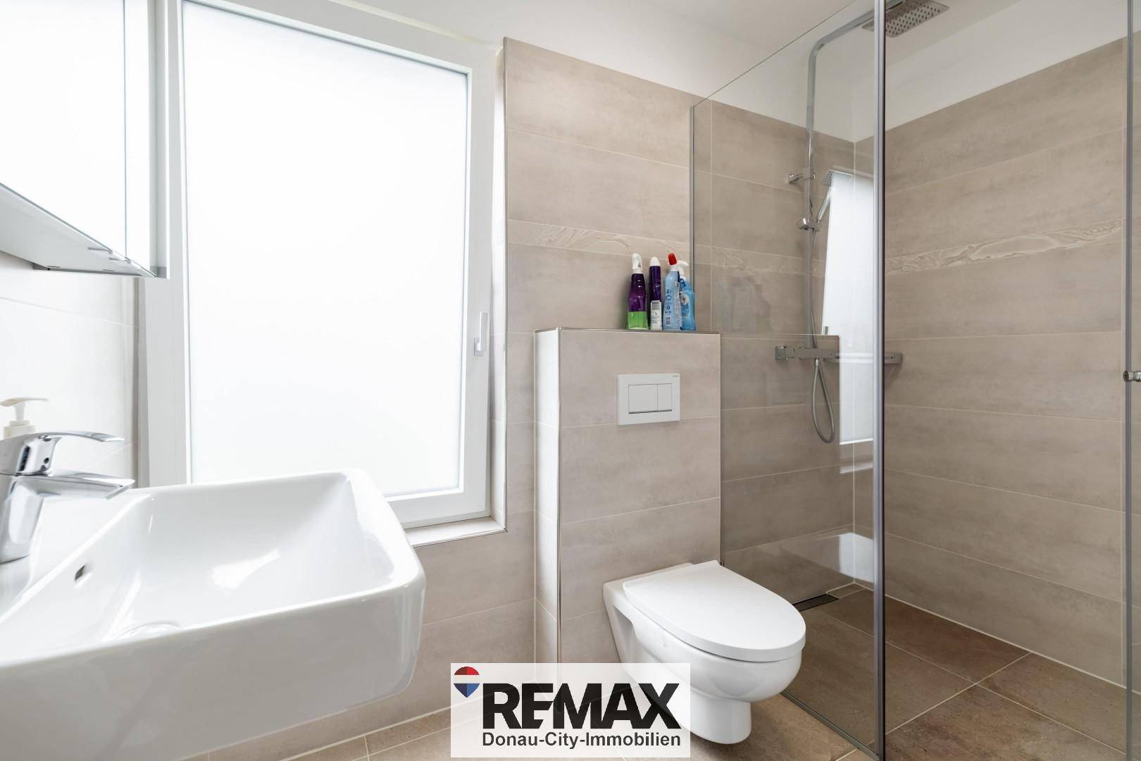 Modernes Badezimmer mit ebenerdiger Dusche, wandhängender Toilette und Fenster für Tageslicht.