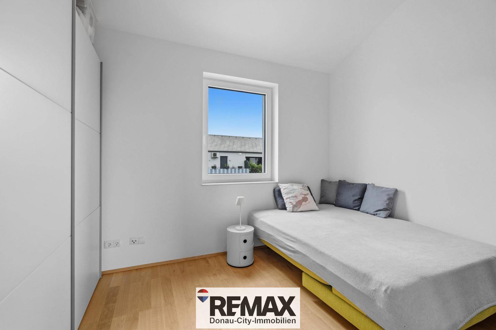 Gemütliches Schlafzimmer mit Einzelbett, weißem Kleiderschrank und Fenster für natürliches Licht.