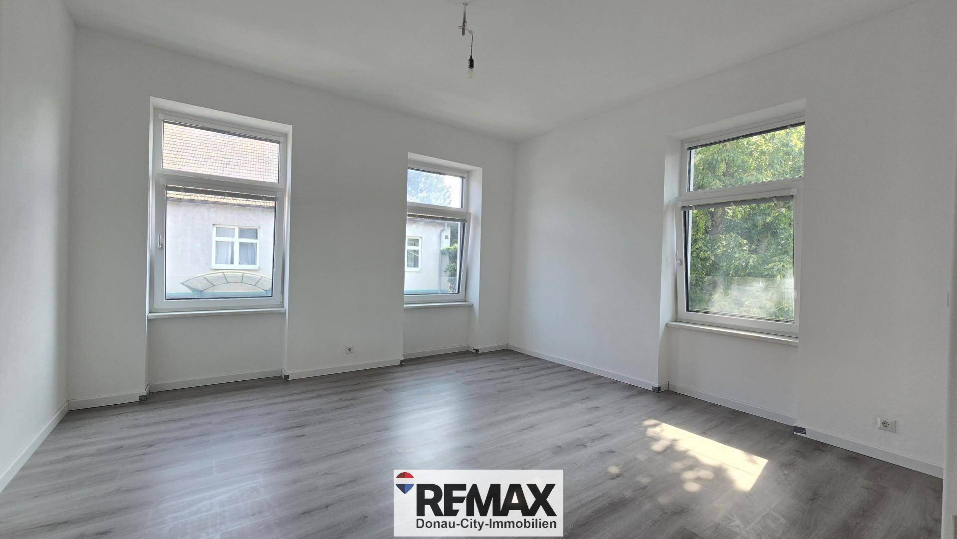 Heller Raum mit modernem Laminatboden und drei Fenstern, bietet viel Tageslicht.