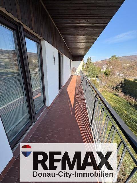 Langer Balkon mit Fliesenboden und Metallgeländer, bietet einen weiten Blick ins Grüne.
