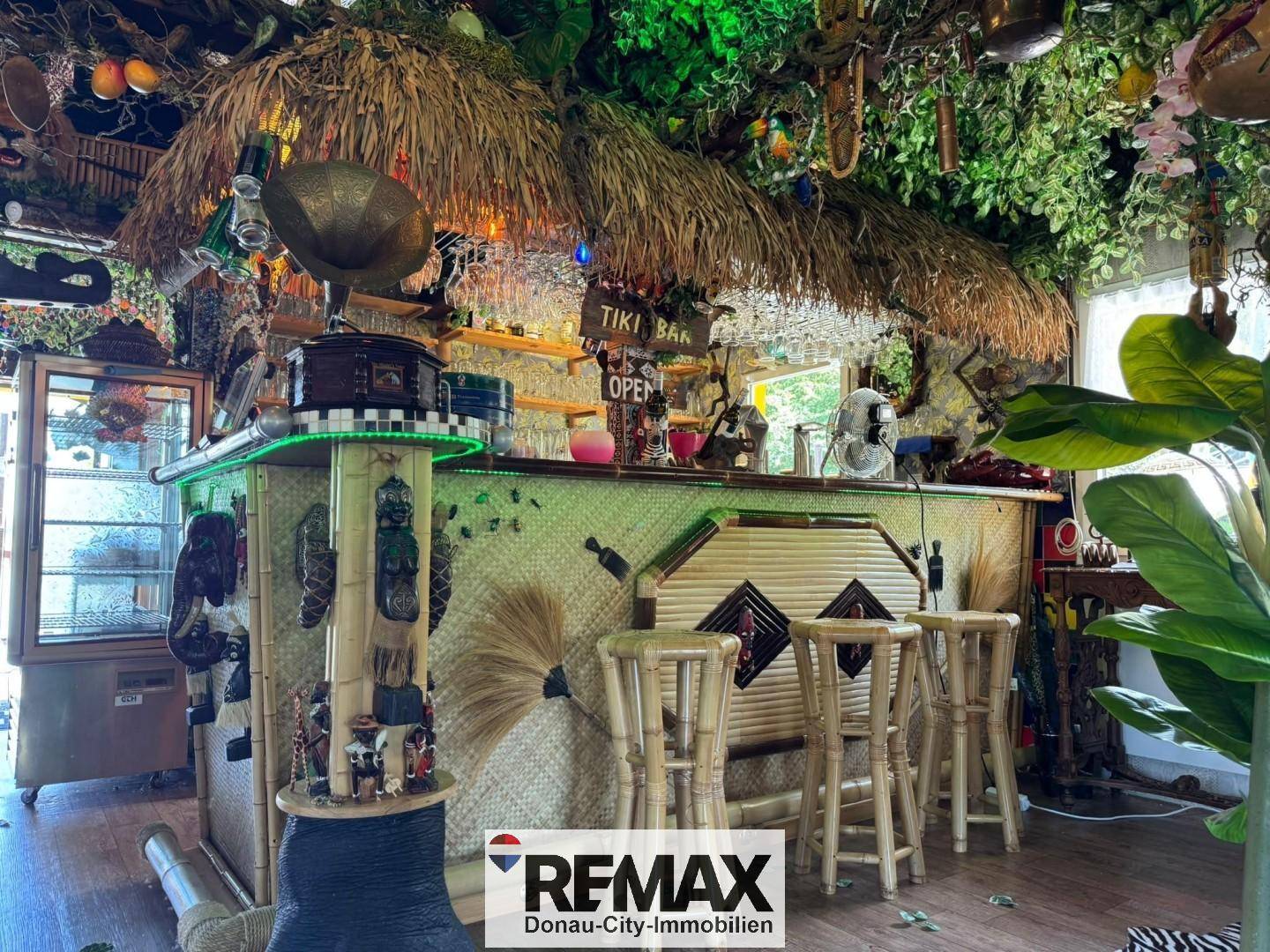 Detailansicht der Tiki-Bar mit beleuchteter Theke, Barhockern und vielen Gläsern, bereit für Gäste.