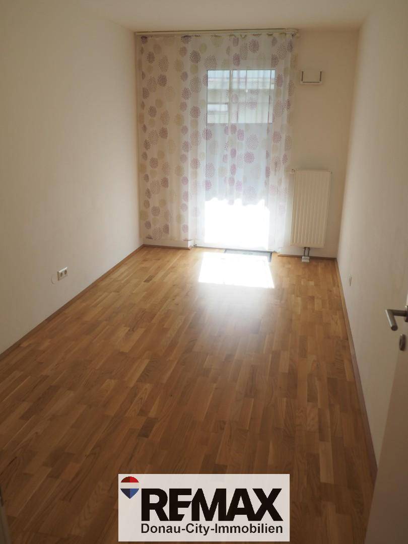 Freundliches Zimmer mit Parkettboden und viel Tageslicht, ideal als Kinder- oder Arbeitszimmer.
