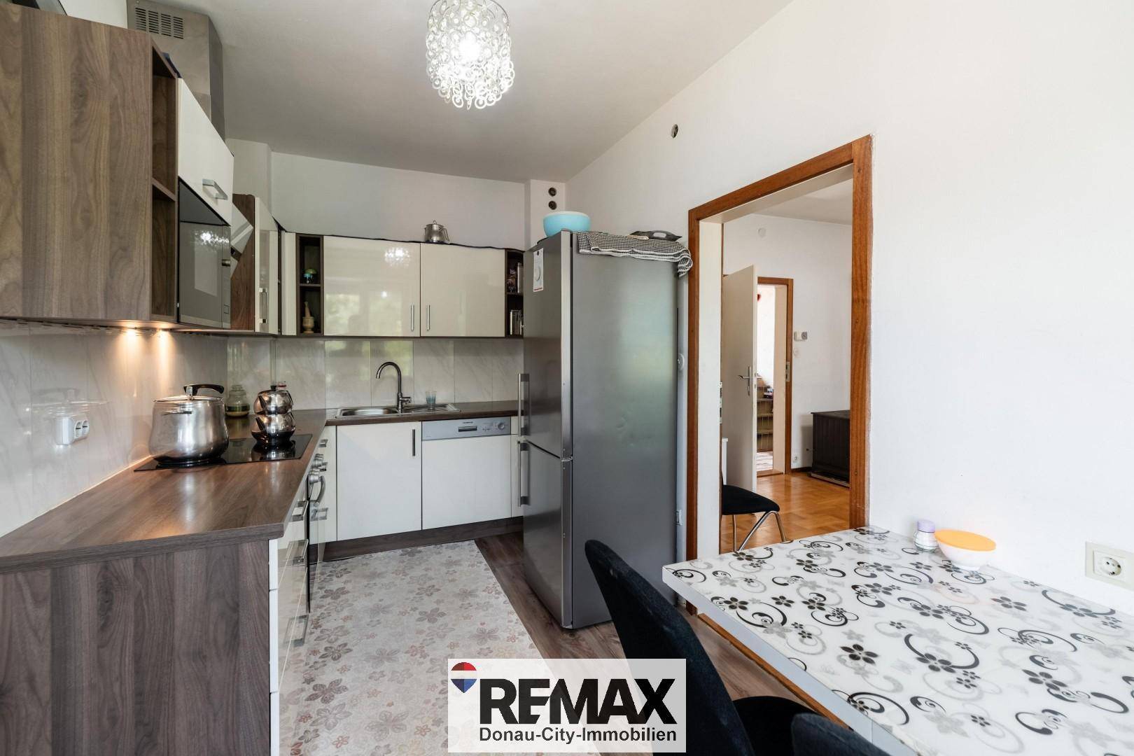 Moderne Küche mit zweifarbigen Schränken, Edelstahlkühlschrank und Essbereich.