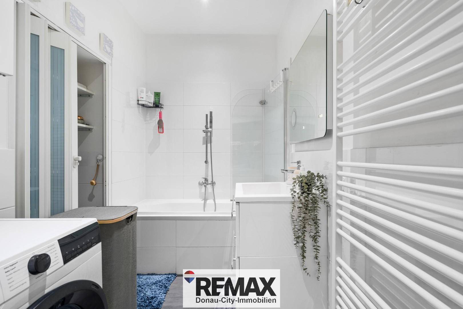 Modernes Badezimmer mit Badewanne, Dusche, Waschbecken und beheiztem Handtuchhalter.