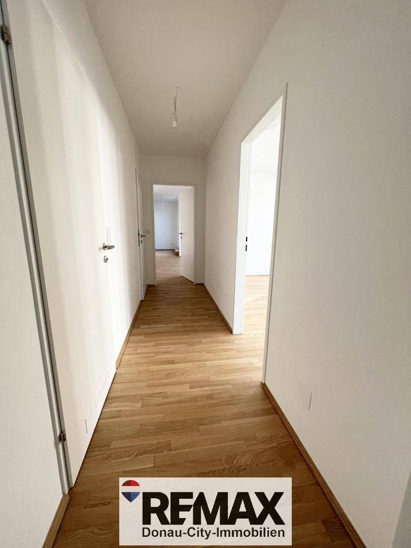 Langer, heller Flur mit Parkettboden und mehreren Türen zu angrenzenden Zimmern.