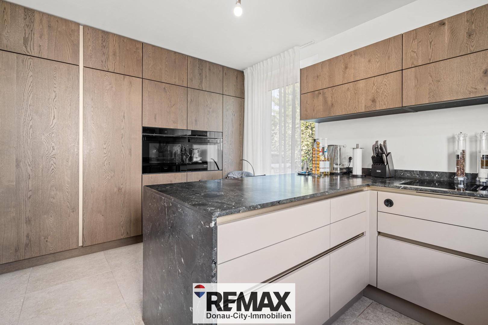 Elegante Küche mit dunkler Arbeitsplatte, Holzschränken und integrierten Backöfen.