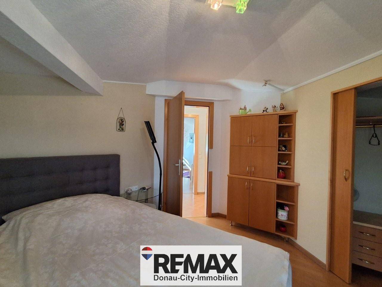 Gemütliches Schlafzimmer mit Doppelbett, Holzschränken und Zugang zu einem weiteren Raum.