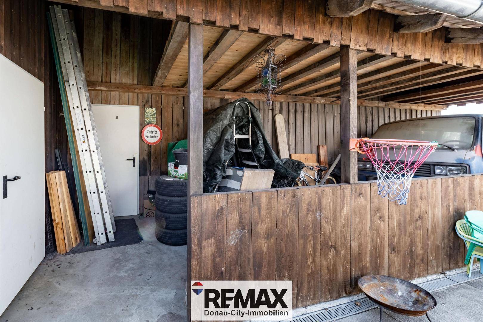Überdachter Bereich mit Holzverkleidung, Lagerung für Reifen und Leitern, sowie einem Basketballkorb.