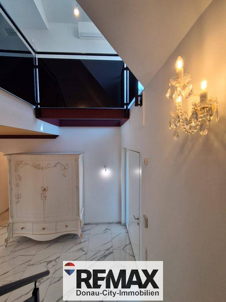 Heller Flur mit Marmorfliesen, eleganter Wandbeleuchtung und Blick auf die obere Etage.