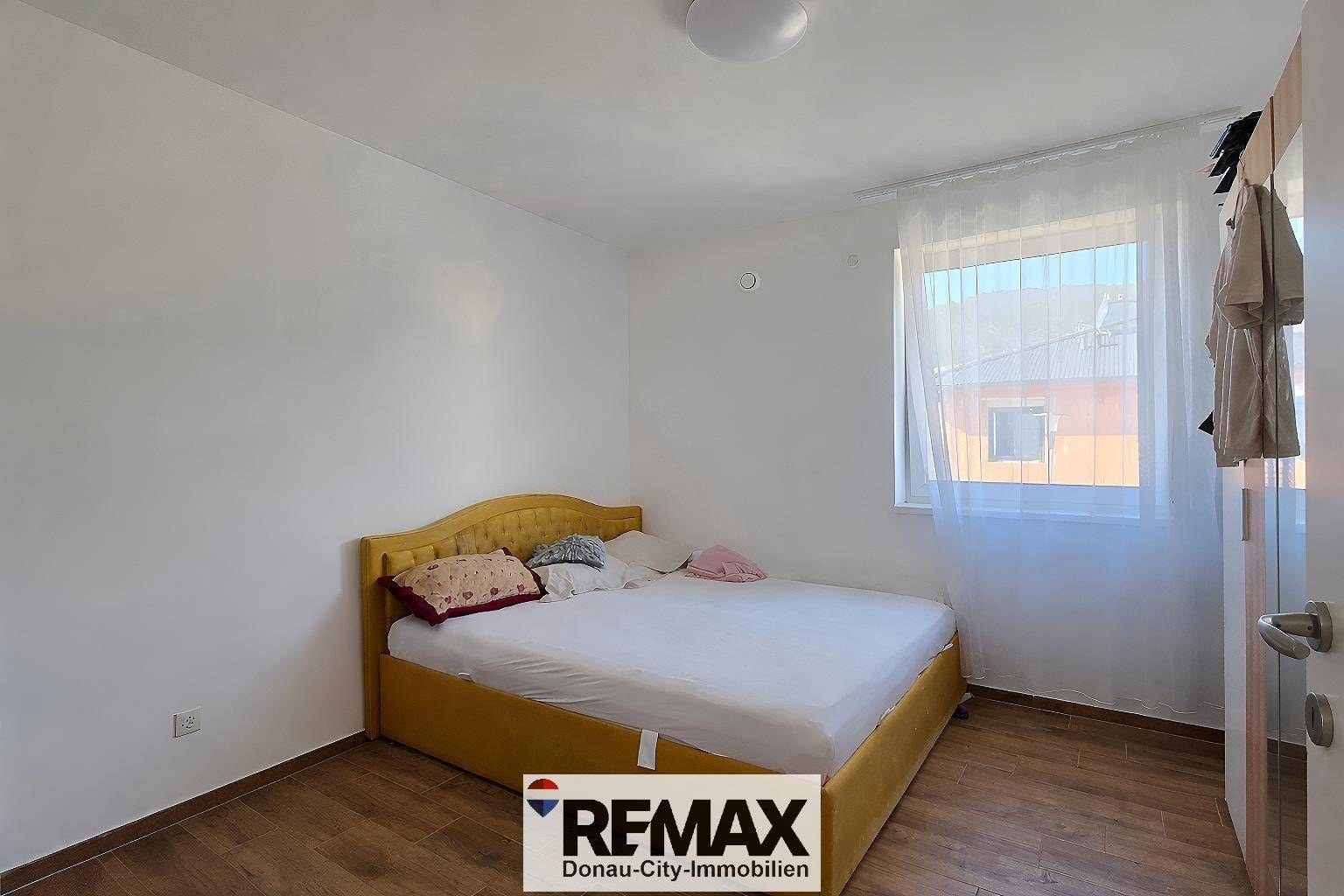 Gemütliches Schlafzimmer mit gelbem Bettrahmen, Holzboden und einem Fenster für natürliches Licht.