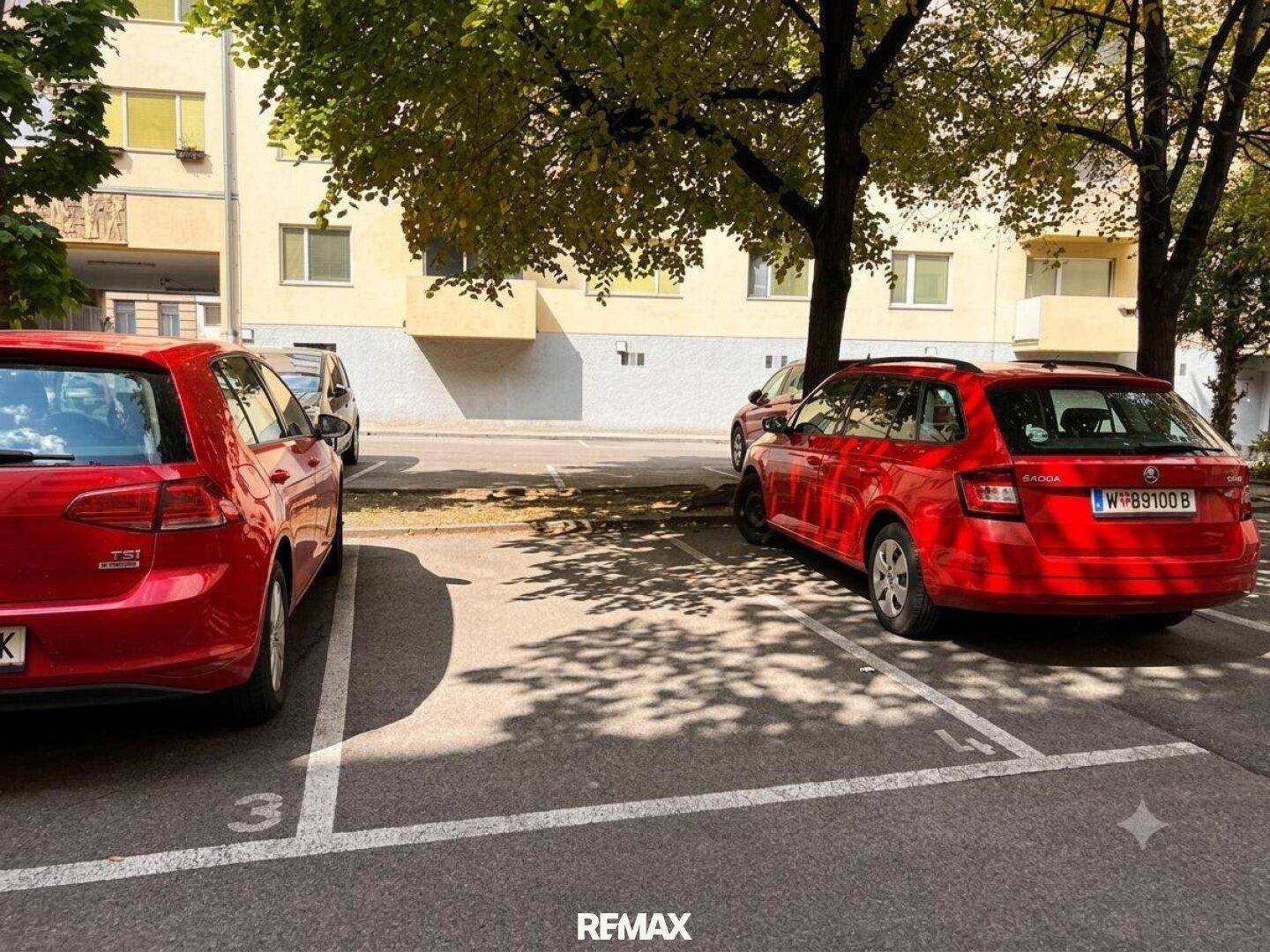 Parkplatz vor dem Gebäude mit markierten Stellflächen und Bäumen.