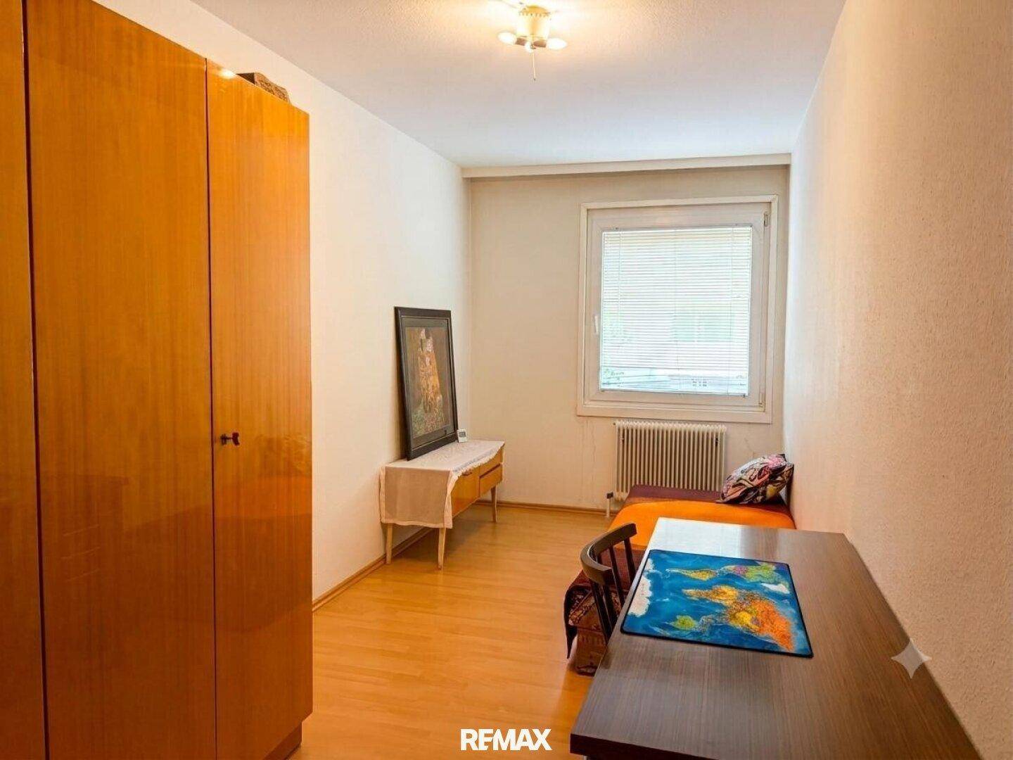 Kinder- oder Gästezimmer mit Einzelbett, Schreibtisch und Holzschrank.