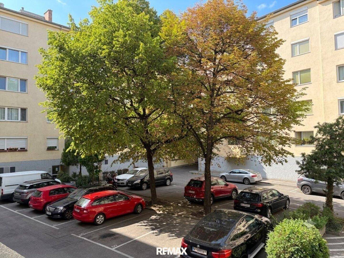 Außenansicht des Gebäudes mit Parkplätzen und Bäumen.