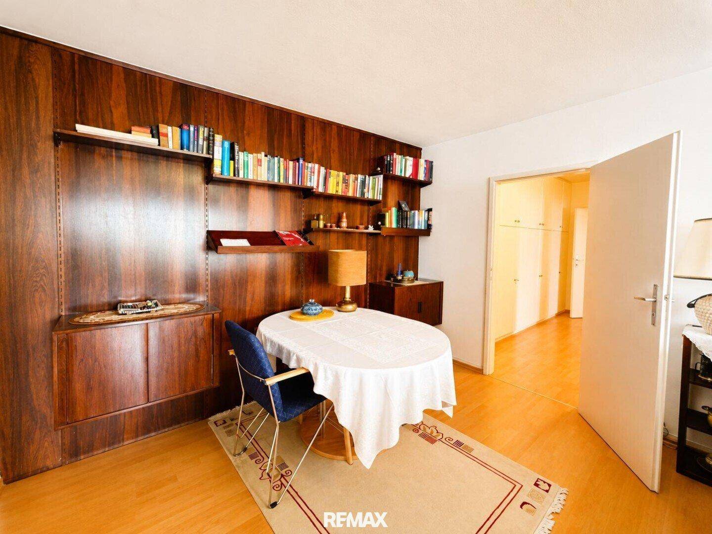 Essbereich mit Holzwandverkleidung, Bücherregalen und ovalem Esstisch.