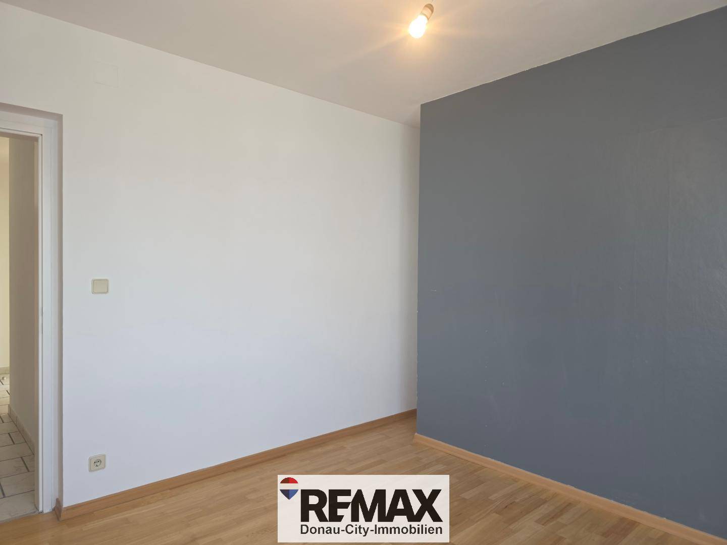 Schlafzimmer mit einer grauen Akzentwand und hellem Parkettboden, bereit zur individuellen Gestaltung.