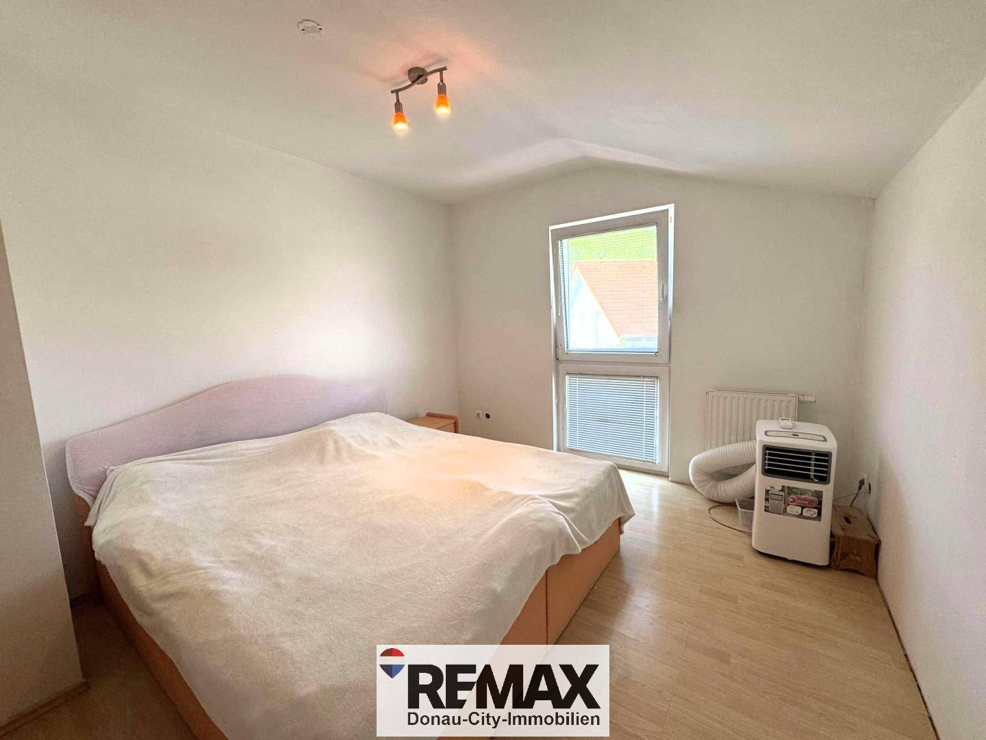 Helles Schlafzimmer mit Holzboden, großem Fenster und ausreichend Platz.