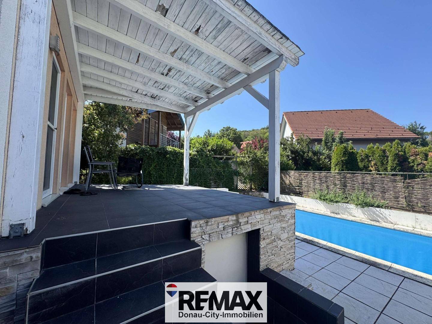 Geräumige Terrasse mit Holzpergola und direktem Zugang zum erfrischenden Poolbereich.
