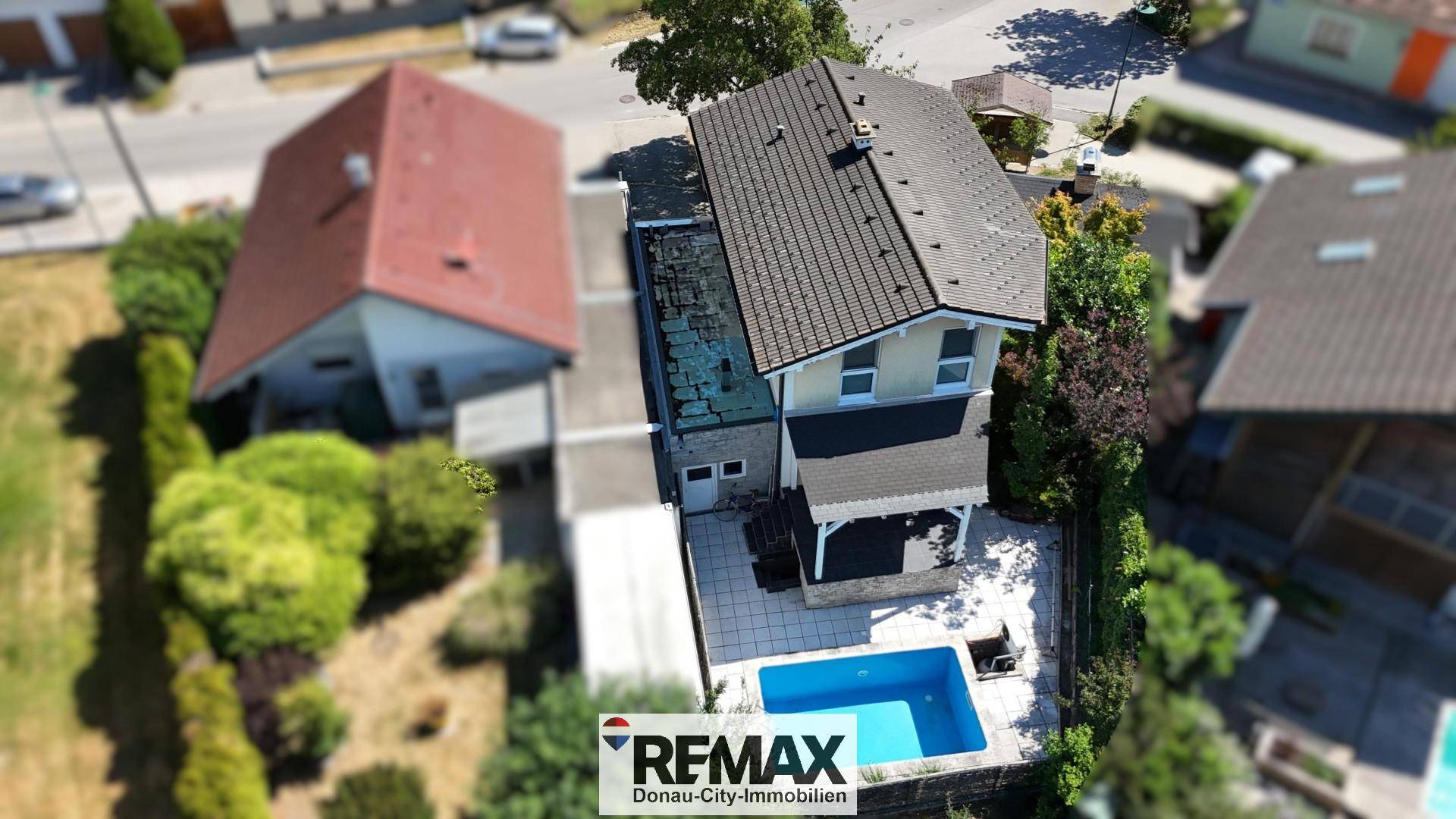 Luftaufnahme des Anwesens mit Haus, Pool und umliegender Wohngegend.