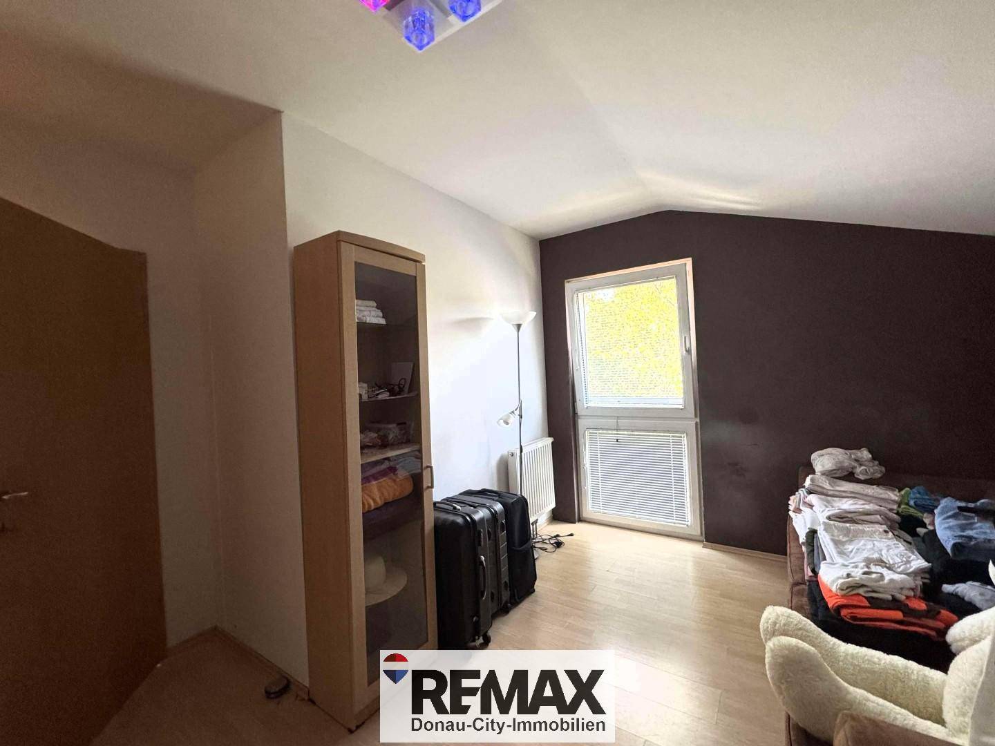 Zimmer mit dunkler Akzentwand, Fenster und hellem Laminatboden, vielseitig nutzbar.