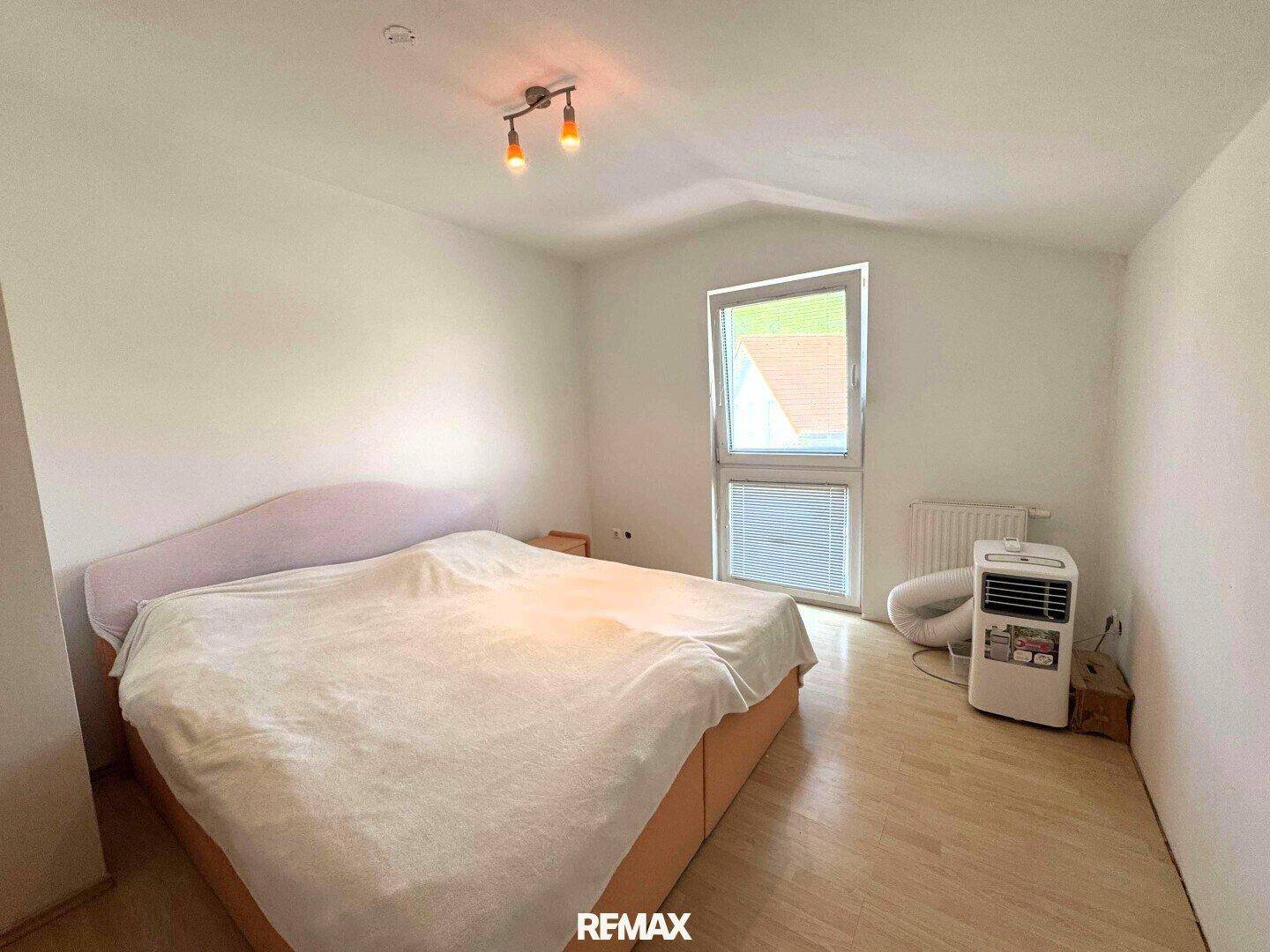 Schlafzimmer mit hellem Holzboden, Dachschräge und Klimaanlage.