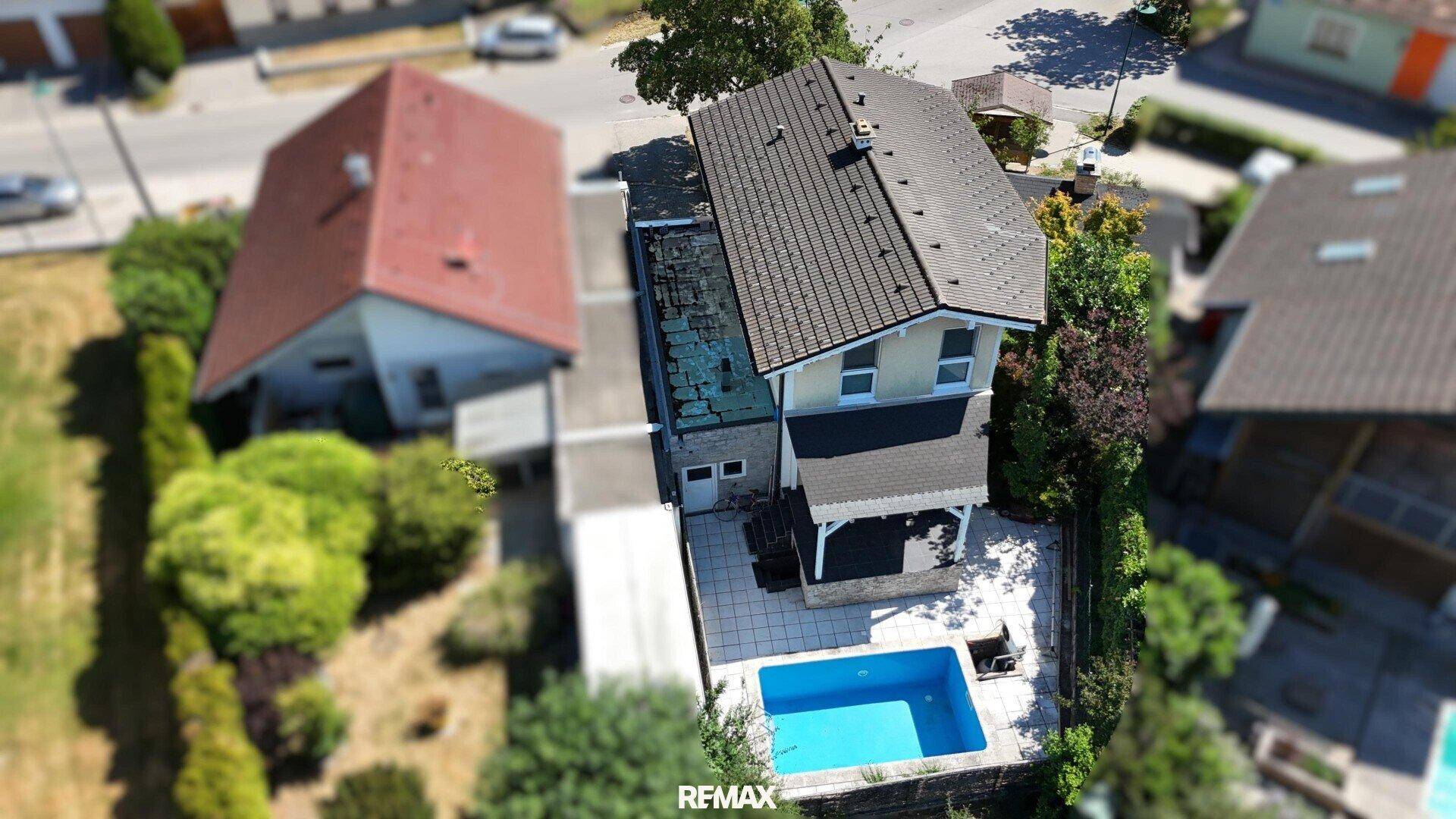 Luftaufnahme des Hauses mit Garten, Pool und umliegender Nachbarschaft.