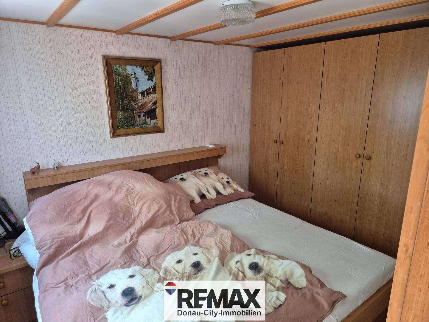 Schlafzimmer mit Doppelbett, großen Holzschränken und Holzbalkendecke.