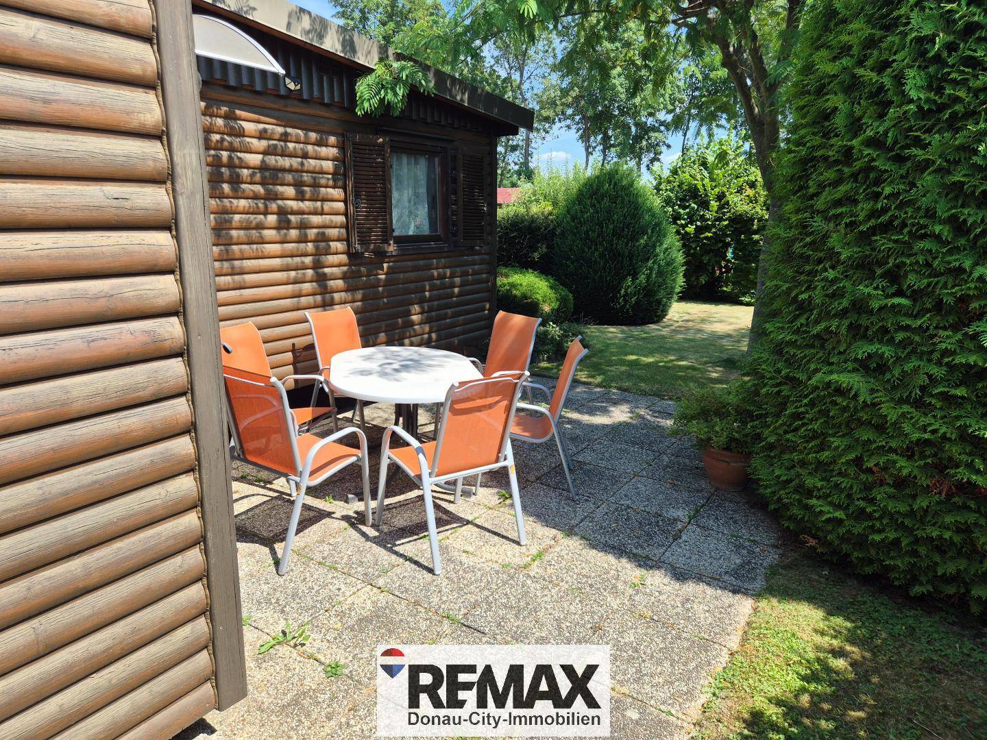 Terrasse mit Gartenmöbeln und Blick auf den grünen Gartenbereich.