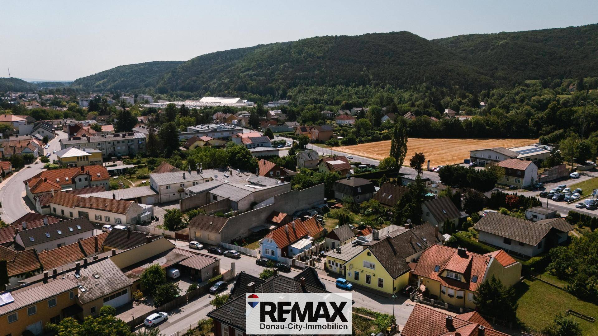 Panoramablick über die Wohngegend mit Häusern, grünen Hügeln und Feldern in der Ferne.