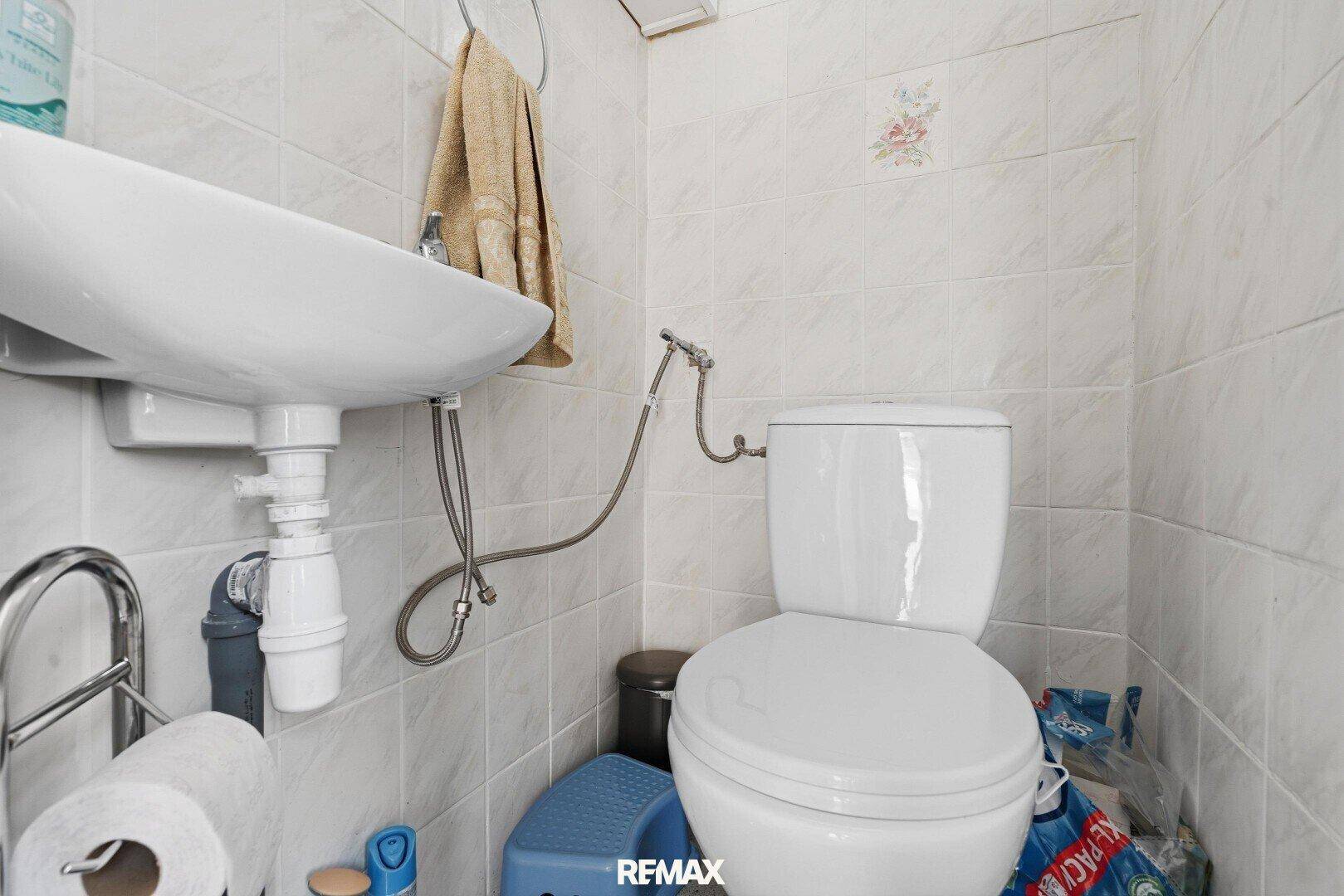 Kleines WC mit Toilette, Waschbecken und Fliesen an den Wänden.