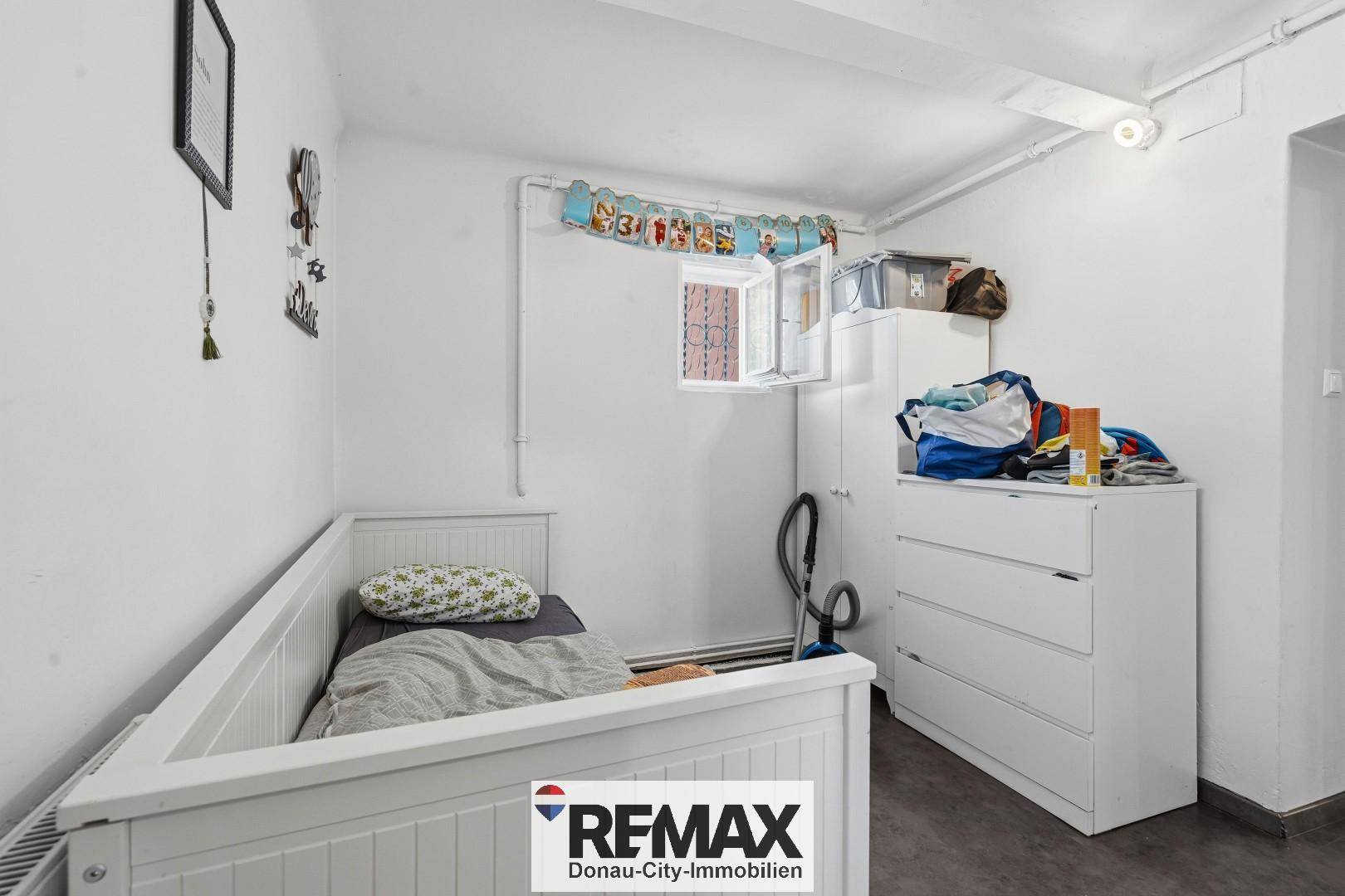 Kleines Schlafzimmer mit Einzelbett, Kommode und kleinem Fenster, ideal als Kinder- oder Gästezimmer.