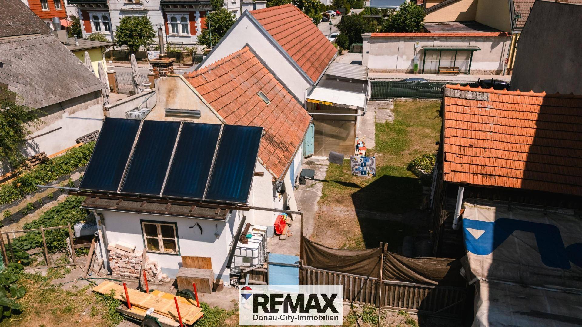 Luftaufnahme des Hauses mit Solaranlage auf dem Dach und angrenzenden Gärten.