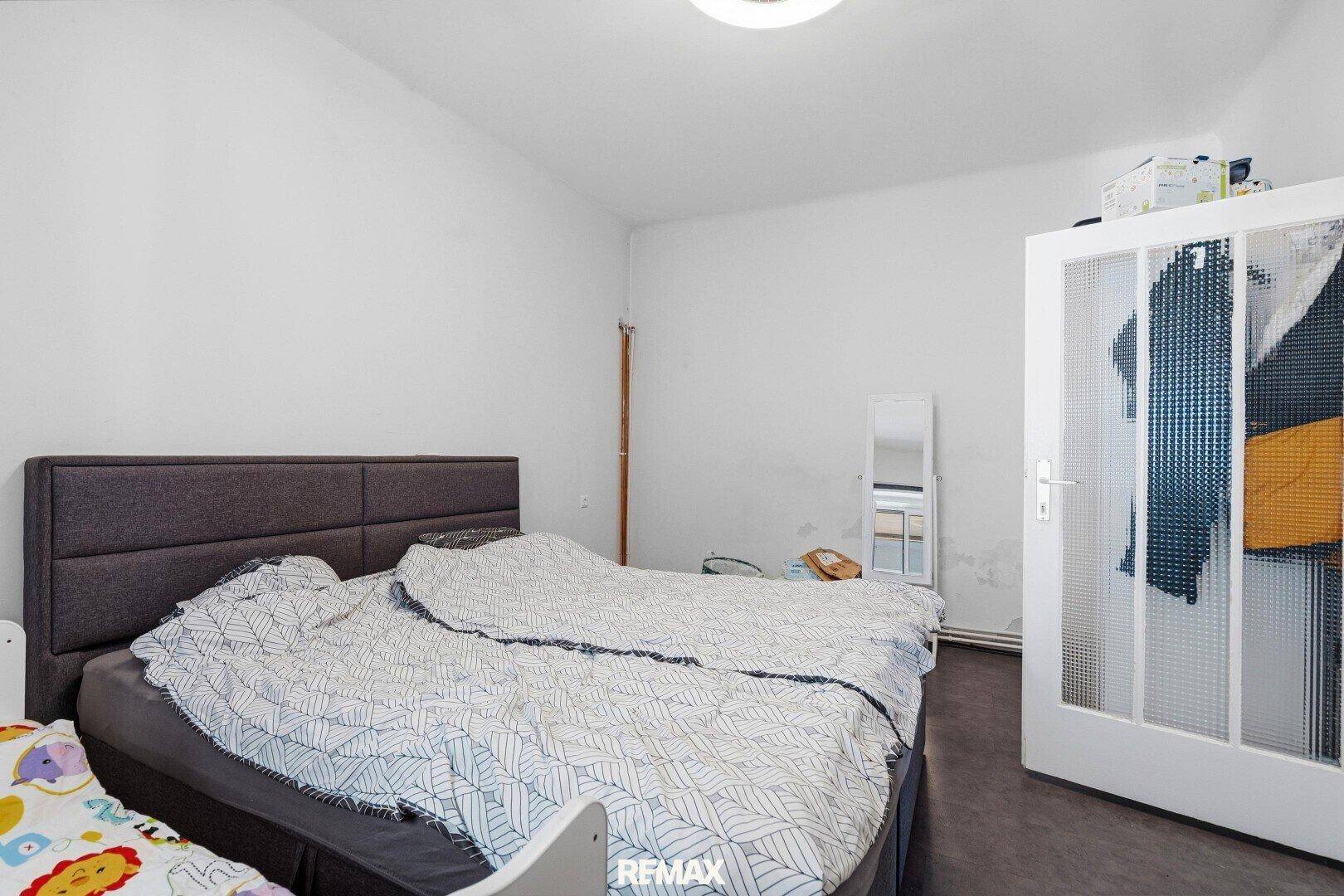 Schlafzimmer mit Doppelbett, weißem Kleiderschrank und schlichtem Design.