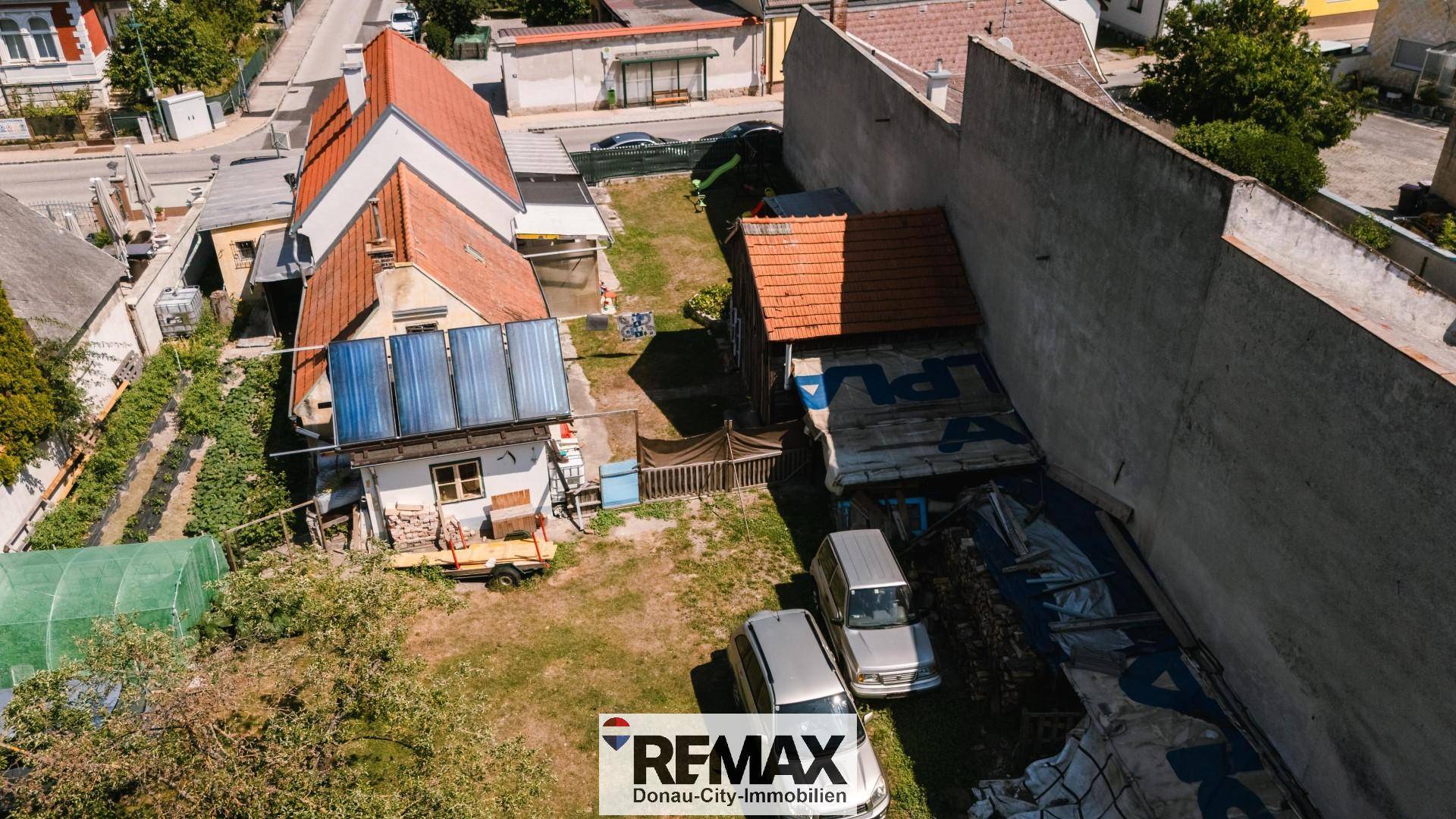 Vogelperspektive des Anwesens mit Nebengebäuden, Garten und geparkten Autos auf dem Gelände.