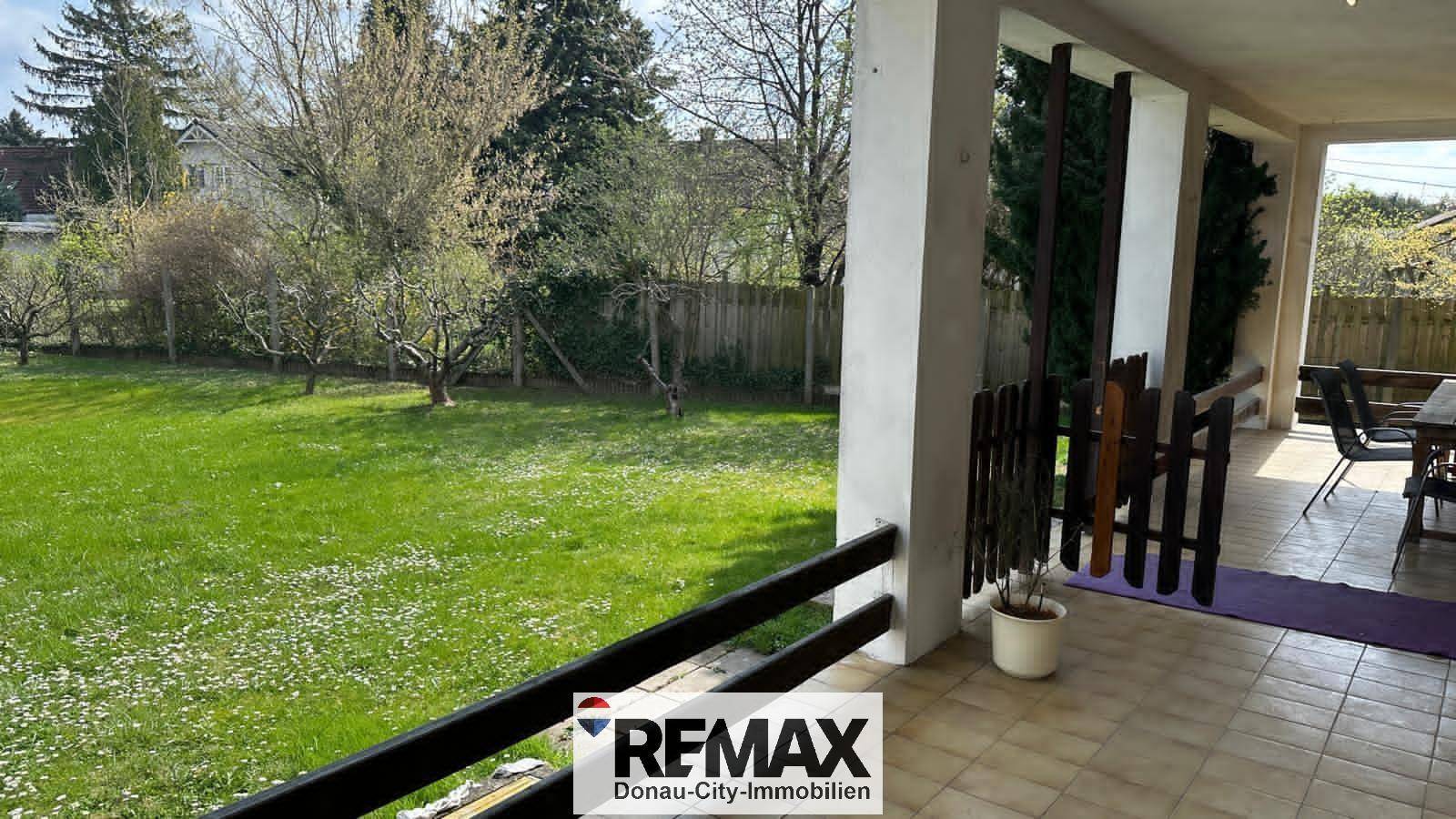 Überdachte Terrasse mit Blick auf den grünen Garten und die umliegende Natur.