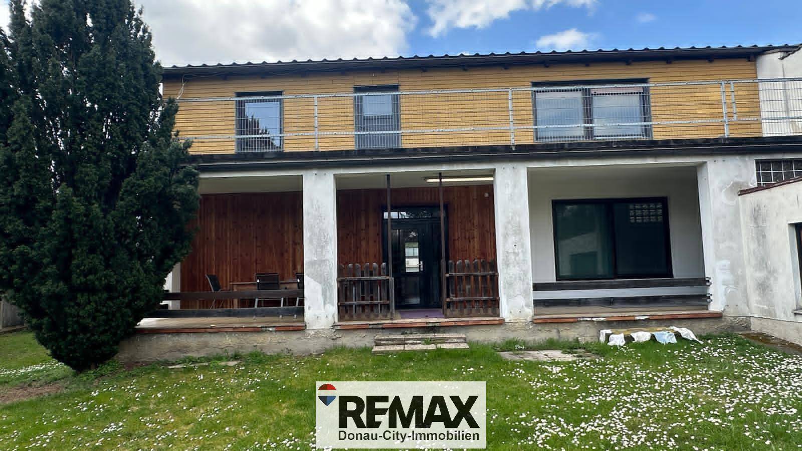 Rückseite des Hauses mit überdachter Terrasse, Balkon und großem, gepflegtem Garten.